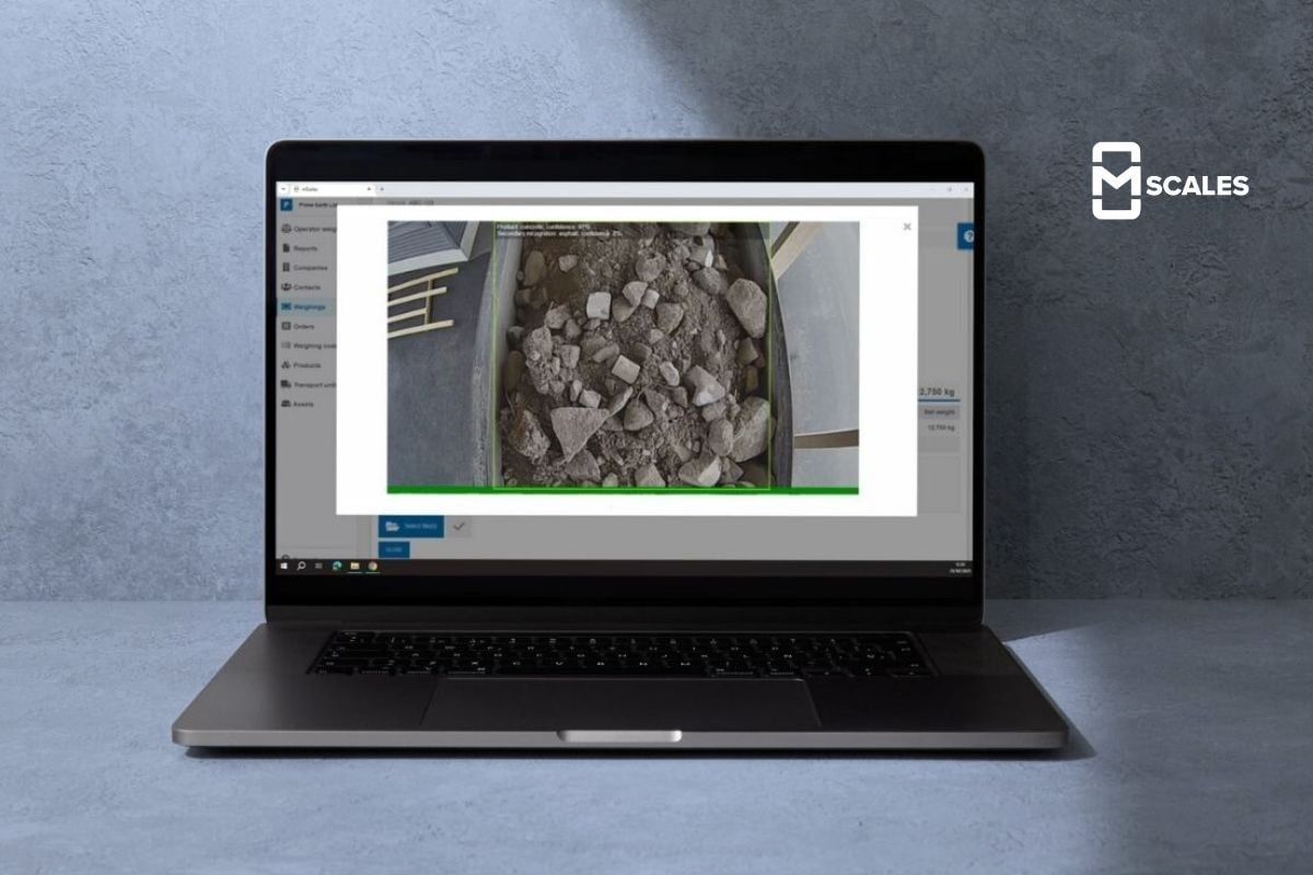 Laptop displaying the mScales user interface with the load recognition feature visible, set against a grey background