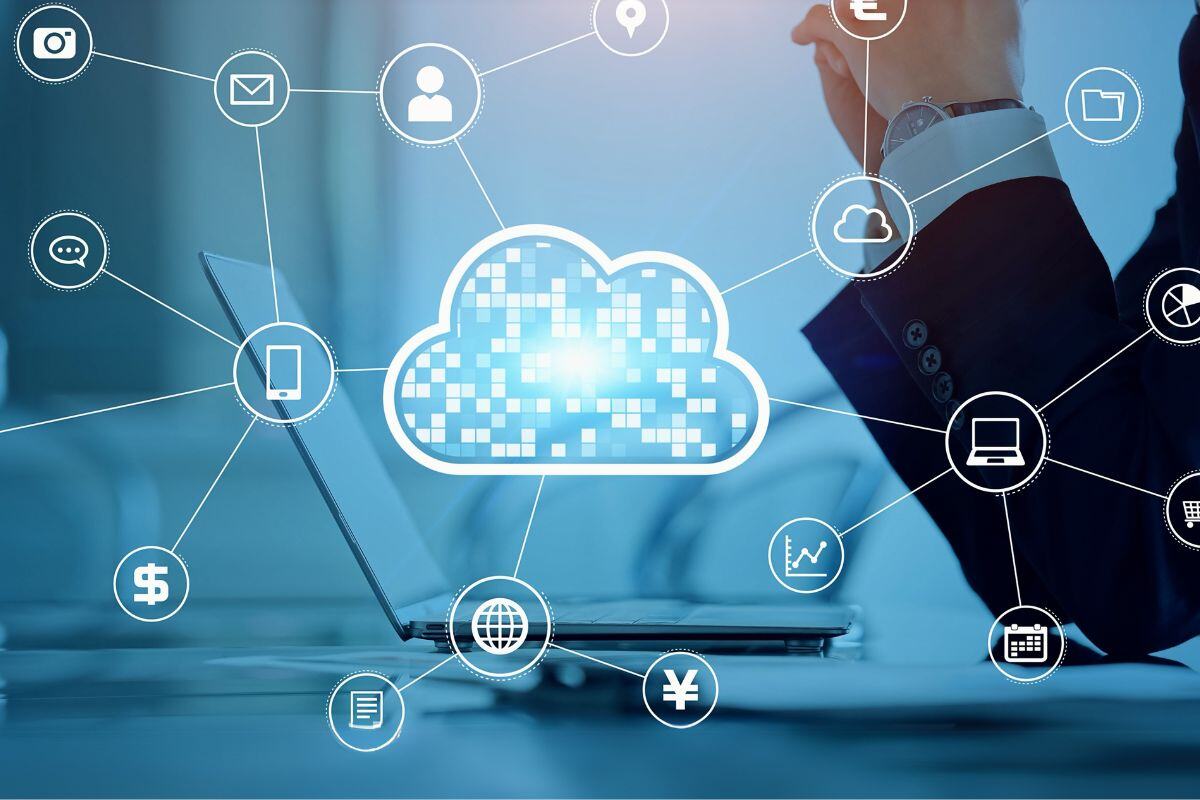 Digital illustration of cloud computing with a central cloud icon surrounded by symbols for online services like email, social media, and devices, with a person in a business suit in the background suggesting a professional tech context.